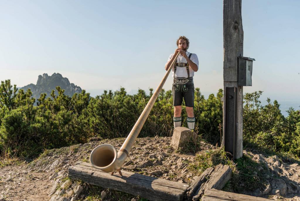 Bayern-Botschafter und Musiker Christian Loferer spiel Alphorn am Gipfel