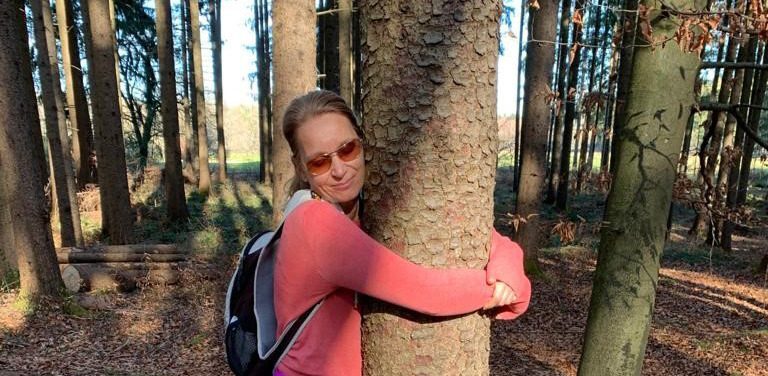 Schon mal einen Baum umarmt? Claudia Mitchell umarmt achtsam einen Baum im Wald.