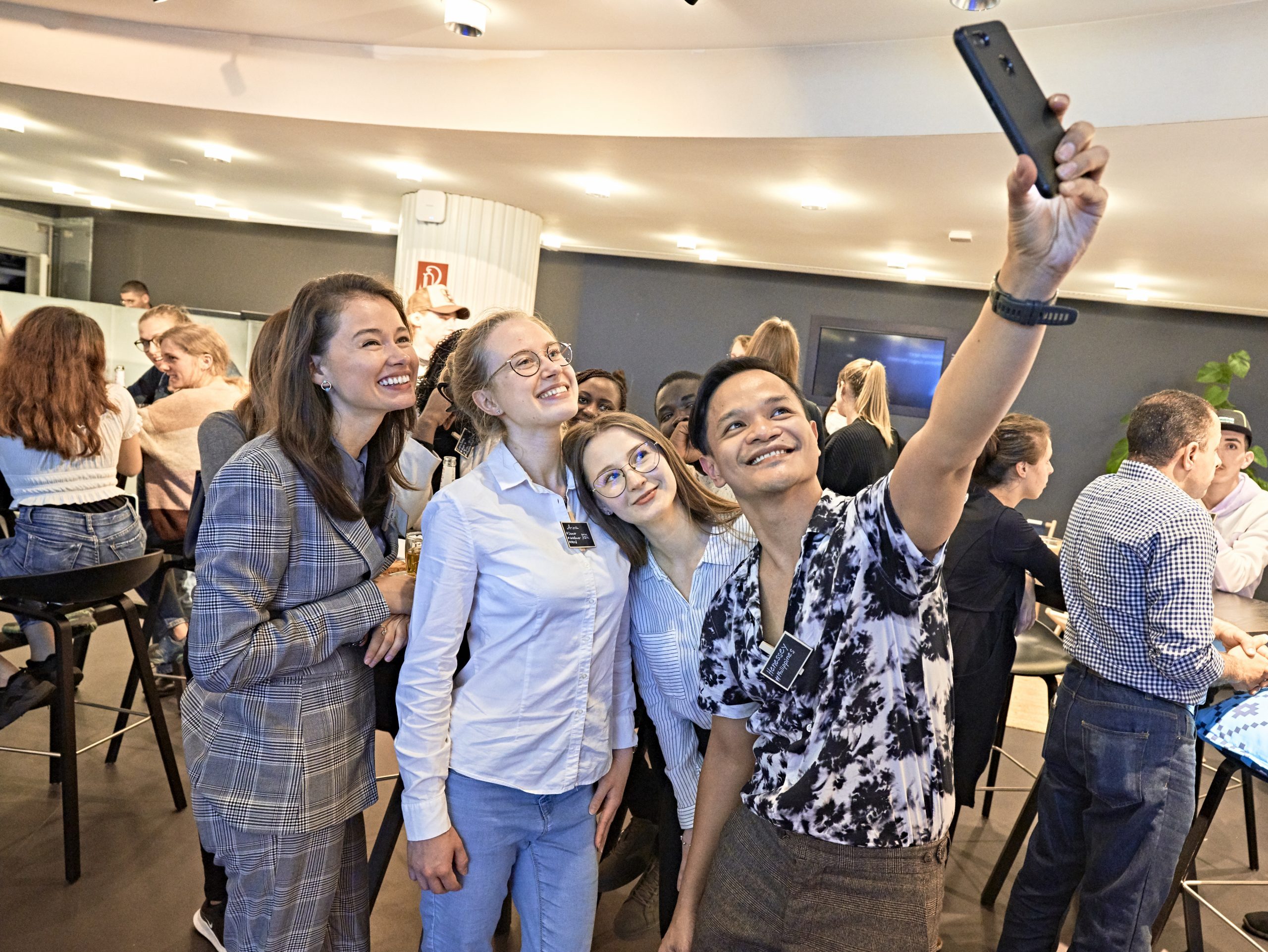 Eine Gruppe aus 4 jungen Touristiker*innen macht ein Selfie bei der Veranstaltung "Tourism Next - Bayerns junges Netzwerk".